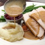 turkey gravy over mashed potatoes and turkey with green beans and cranberries