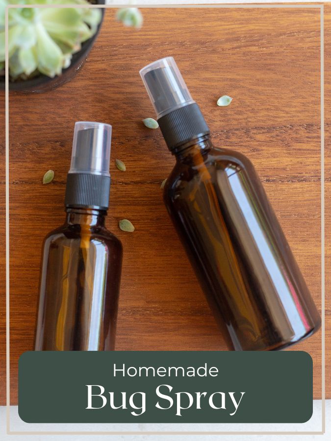Amber spray bottles labeled "Homemade Bug Spray" on a wooden background—DIY herbal mosquito repellent made with natural ingredients.