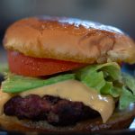 Close-up of a fully assembled lion’s mane burger with lettuce, tomato, and cheese.
