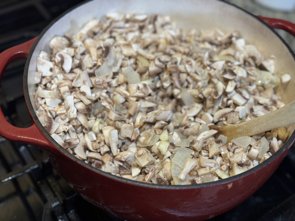 Chopped mushrooms added to sautéed onions in a Dutch oven for homemade cream of mushroom soup